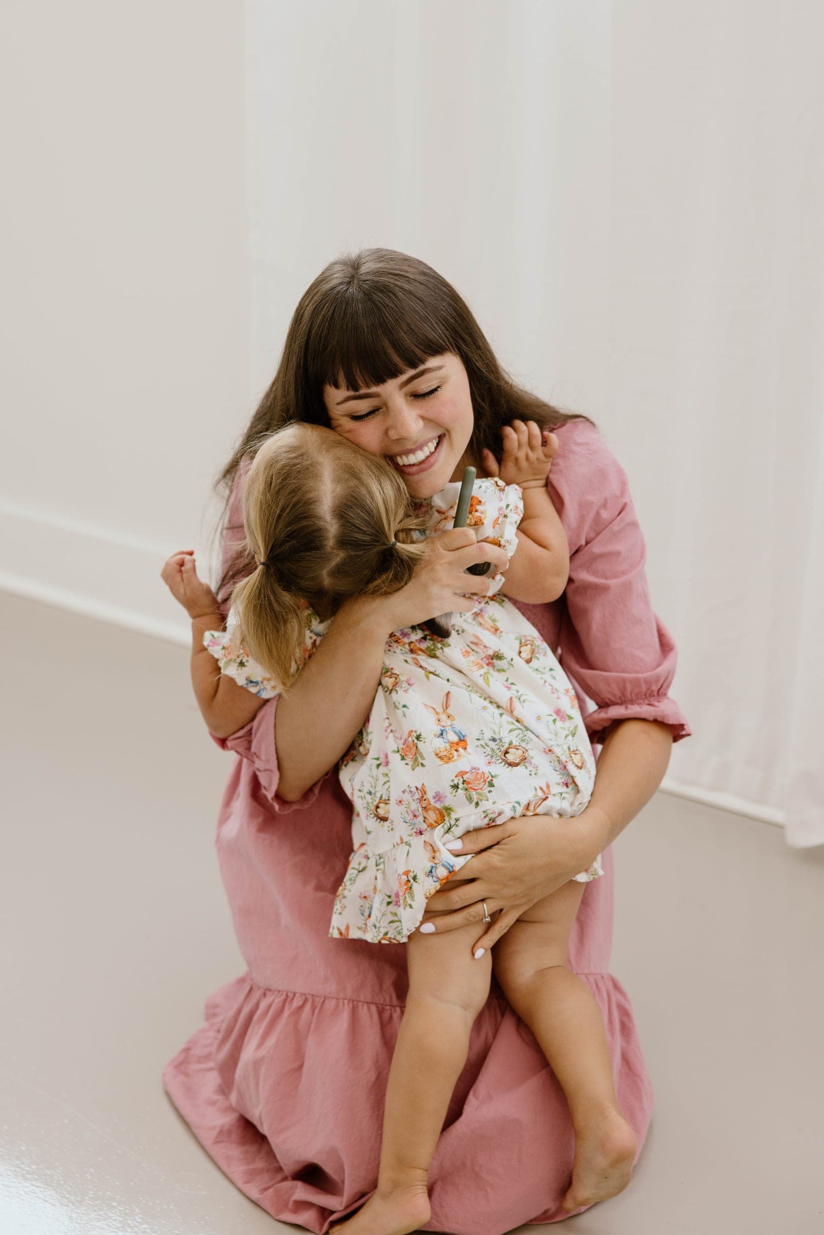 A mother in a cotton dress hugging her daughter