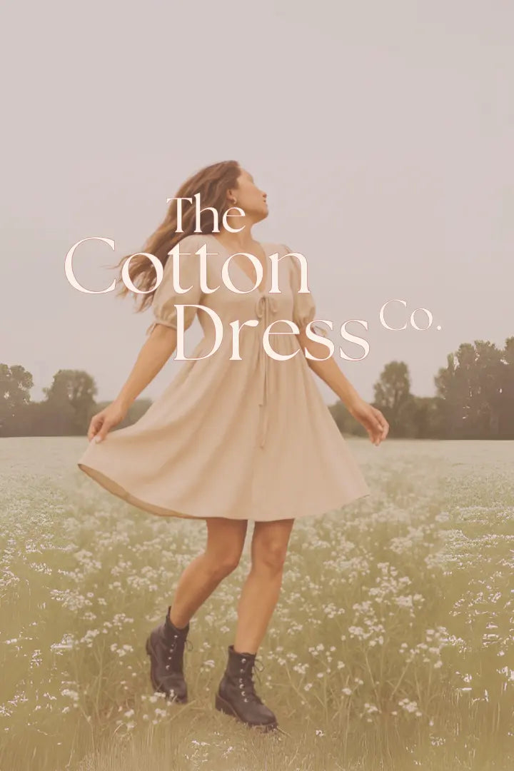 Woman in a dress standing in a field with 'The Cotton Dress Co.' text overlay